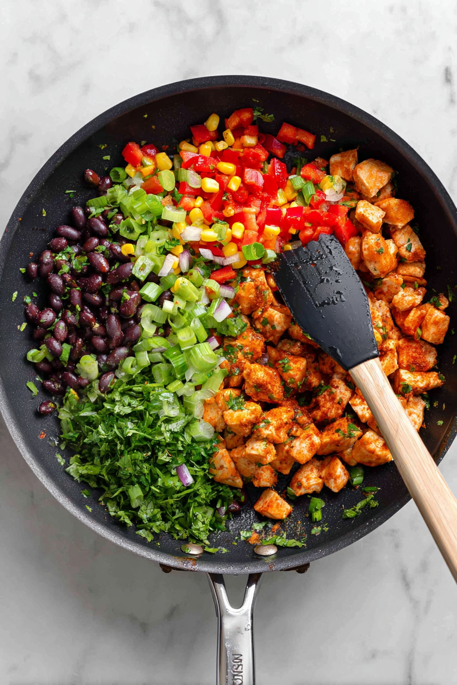 I placed the cooked peppers and onion in to this pan, then added the diced chicken. Then add in the corn, black beans, lettuce, parsley, cumin, chili powder, and cayenne pepper.