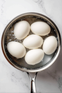 Place the eggs in a single layer in a saucepan and cover them with cold water. Bring the water to a boil over medium-high heat. Once boiling, reduce the heat to low and simmer for 10 minutes.