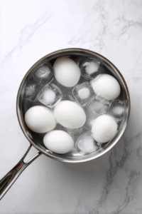 After boiling, remove the eggs from the heat and immediately transfer them to a bowl of ice water to cool. Let them sit in the ice water for about 5 minutes to cool completely.