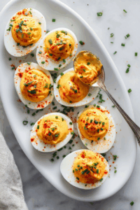 Optionally, sprinkle the filled eggs with paprika for a pop of color, and garnish with chopped fresh chives or parsley for added flavor and presentation.