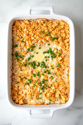 This image shows melted butter being drizzled over a layer of crushed Cheez-Its, evenly coating them for a crispy and buttery topping on the casserole.