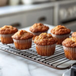 This image shows the freshly baked maple muffins cooling on a wire rack after baking.