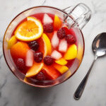 this image shows pina colada sangria in a pitcher garnished with pineapple slices