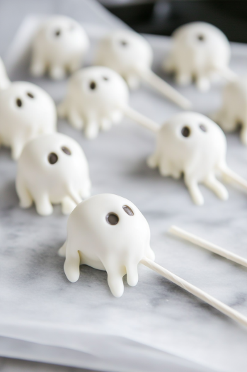 The cake mixture is being pressed into silicone molds on the white marble cooktop. Popsicle sticks are inserted into the flattened tops, and the pops are set aside to chill for 4 hours or overnight.