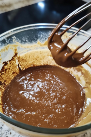 The dry ingredients being added to the wet sugar-yogurt mixture in a mixing bowl on the white marble cooktop, ready to be gently whisked.