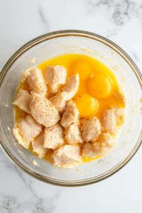 In another bowl, beat the egg and mix with cornstarch, salt, and pepper. Coat chicken thighs pieces in this mixture.