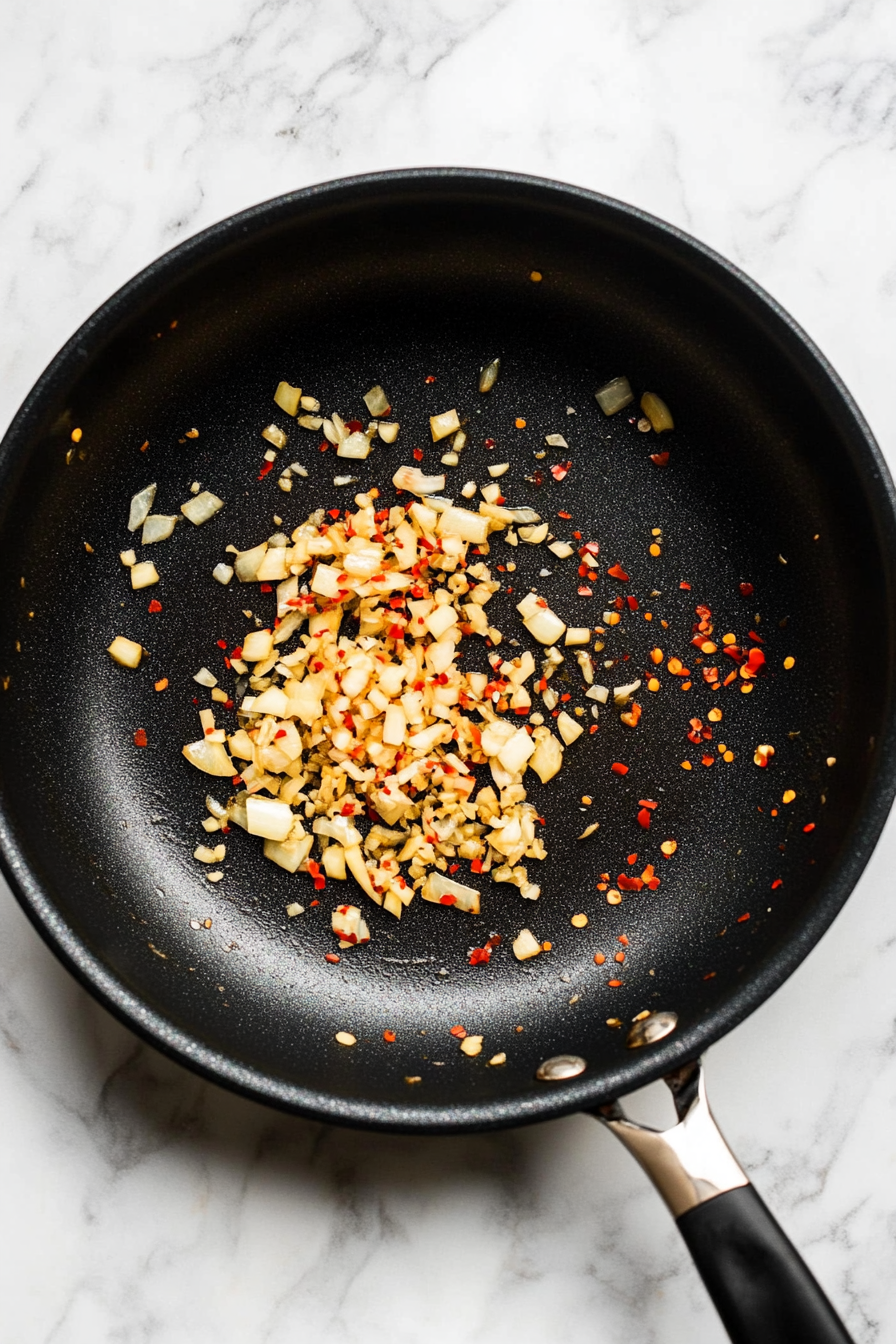 In the same skillet, sauté garlic, ginger, and red pepper flakes until fragrant.