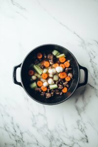 In the same pot, sauté onion, garlic, carrots, and celery until soft.