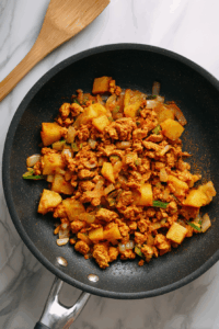 In a pan, cook ground chicken, onions, chopped potato, green chili, and all spices until the mixture is dry and cooked through. Let it cool.