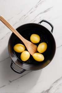 Heat 2 tbsp oil in a pot, fry halved potatoes until golden, then remove and set aside.