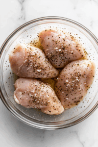 Season chicken breasts with salt, pepper, and half the oregano.