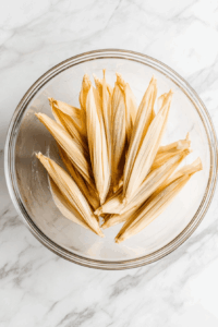 Soak corn husks in hot water until soft and pliable.