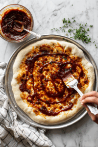 Spread BBQ sauce evenly over the crust.