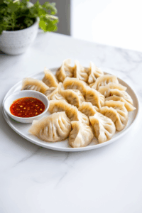 Delicious Steamed Chicken Momos at Home: Serve hot with your favorite dipping sauce like Shack Sauce or enjoy with a chilled glass of Russian Apple Kvas.