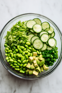 Add cucumbers, edamame, avocado, and green onions to a large mixing bowl.