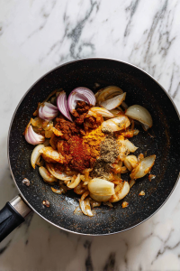 Add chopped onions, cook until translucent, then mix in turmeric, red chilli powder, salt, and homemade kadai masala.