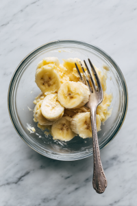 In a mixing bowl, mash the ripe bananas.
