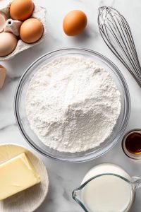 Mix dry ingredients: In a bowl, whisk flour and baking powder. Mix wet ingredients: In another bowl, beat eggs, sugar, melted butter, milk, and vanilla.