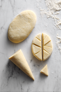 Divide dough into balls, roll each into an oval, cut in half, and shape into cones.