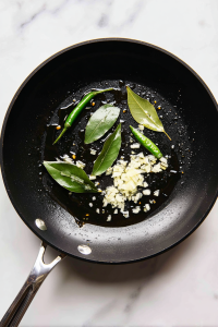 In the same pan, heat more oil and butter, add bay leaf, green chili, and chopped onion.
