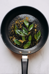 Add remaining oil, mustard seeds, cumin seeds, and curry leaves; let them splutter.