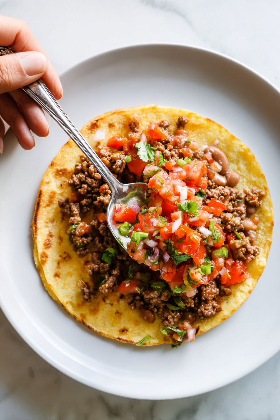 Spread refried beans on half of the tortillas, then layer with seasoned beef.
