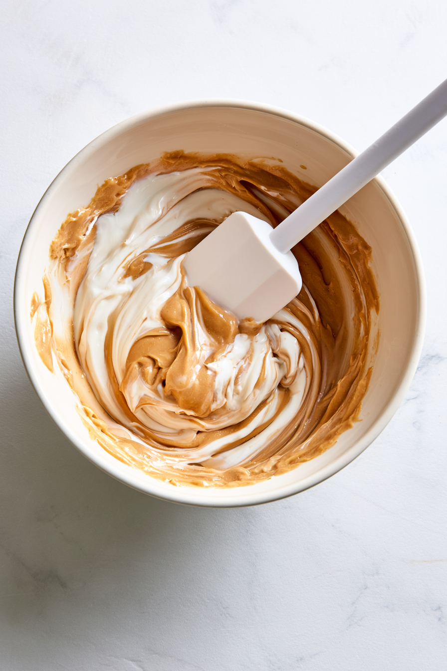 In a mixing bowl, combine Greek yogurt, peanut butter, maple syrup, and vanilla extract